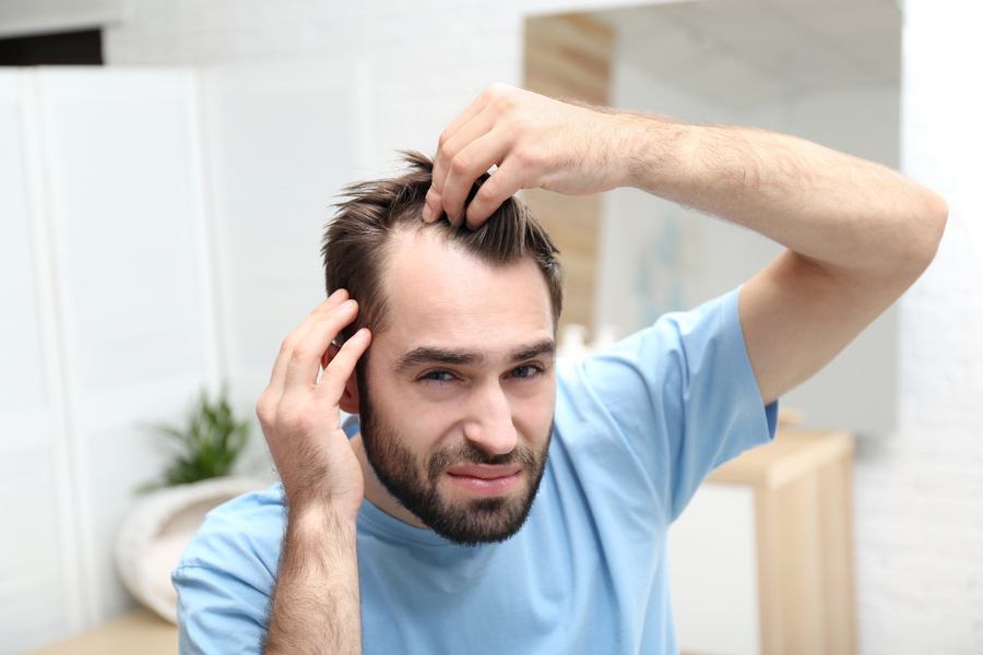 Um homem de meia-idade olha-se ao espelho e pergunta-se qual será a melhor altura para fazer um transplante capilar.