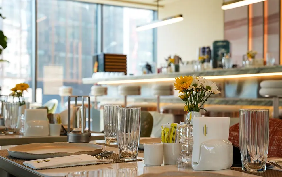 Decoração de mesa no Elitoria Hotel com flores brancas e amarelas em primeiro plano